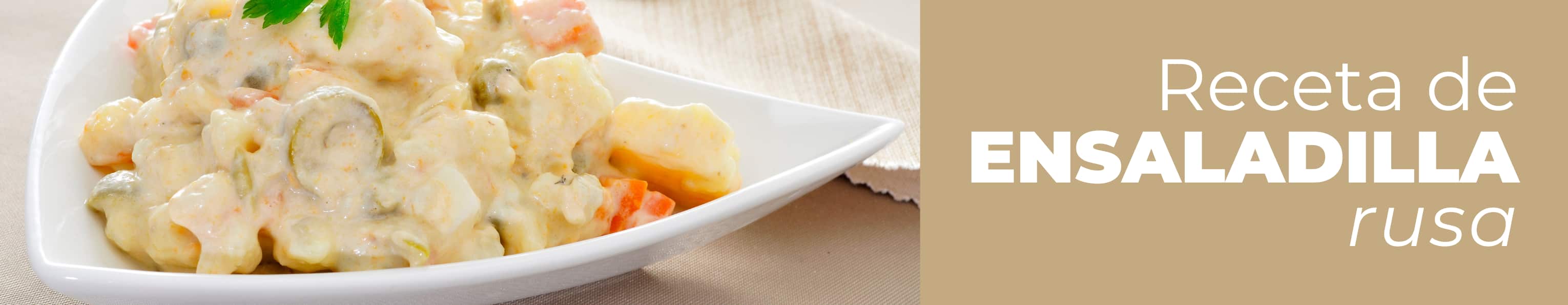 Fuente de cerámica con una ensaladilla rusa con mayonesa casera ya terminada y decorada con aceitunas.